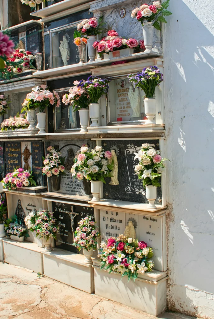 Alignement de niches funéraires fleuries d'un columbarium, sous un ciel bleu.
