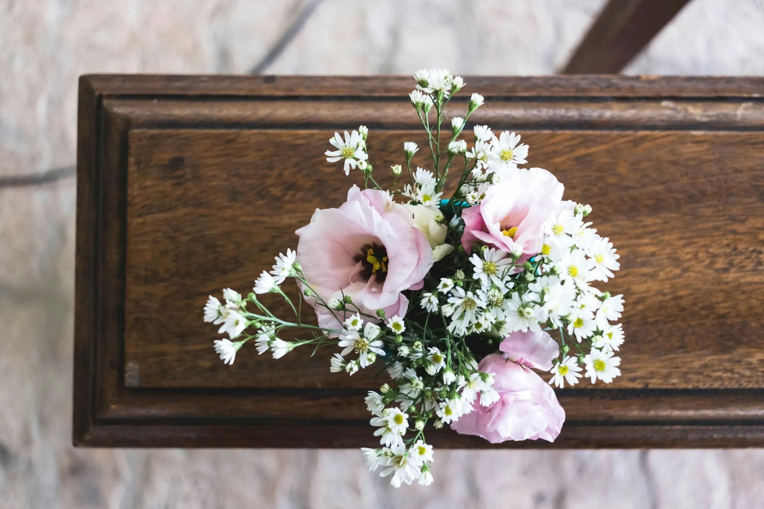 Composition florale de roses roses et de petites fleurs blanches sur un meuble en bois.