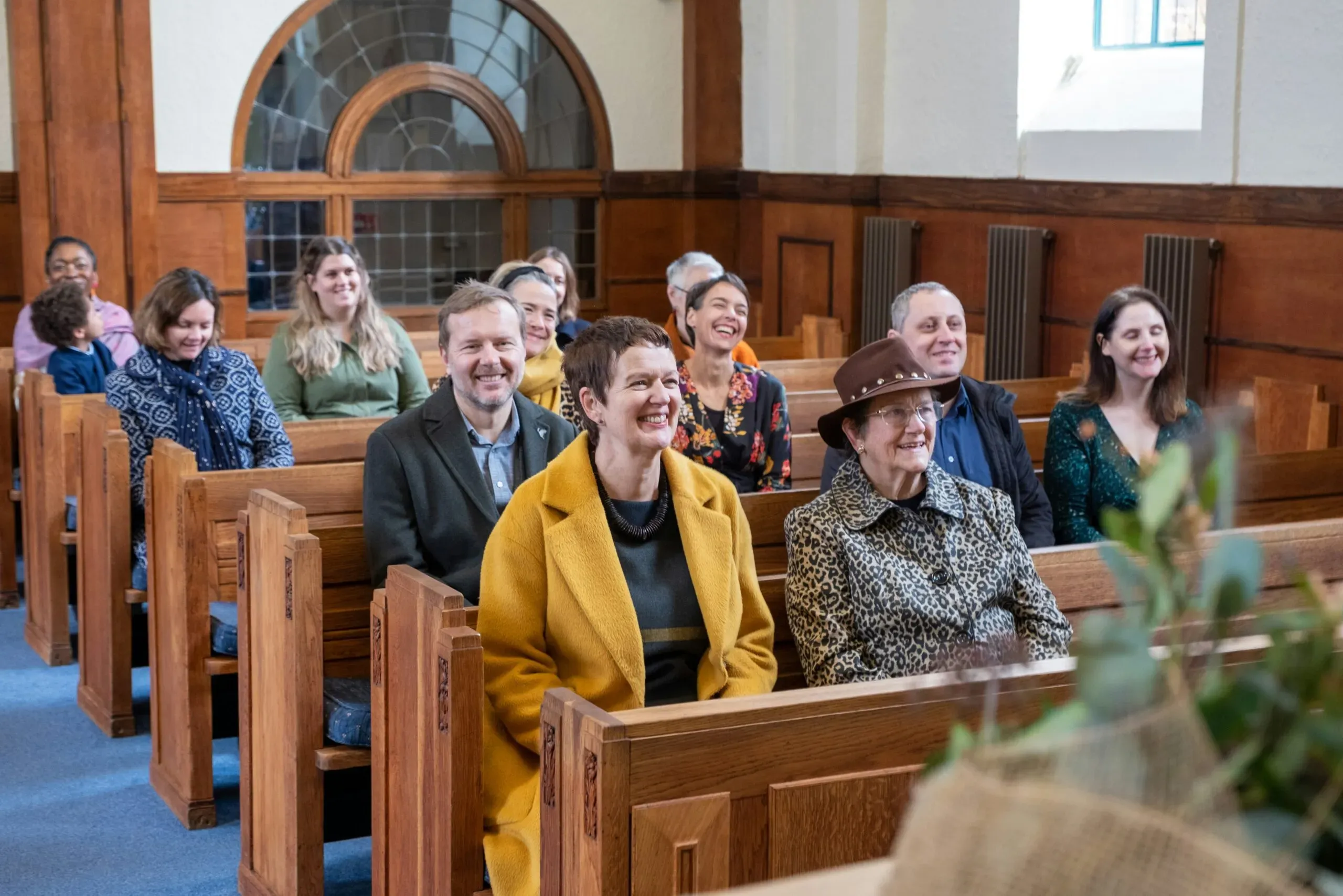 Assemblée souriante assise sur les bancs d'une église.