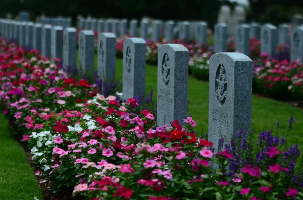 Stèles funéraires grises alignées derrière une bordure de fleurs colorées.
