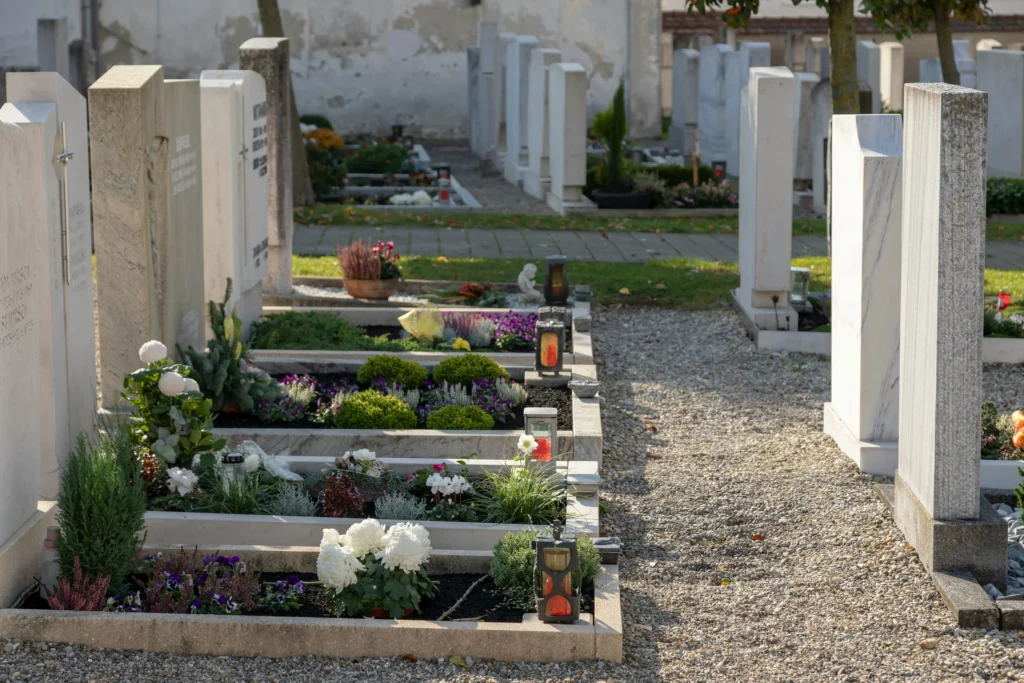 Allée gravillonnée d'un cimetière avec des tombes individuelles fleuries.